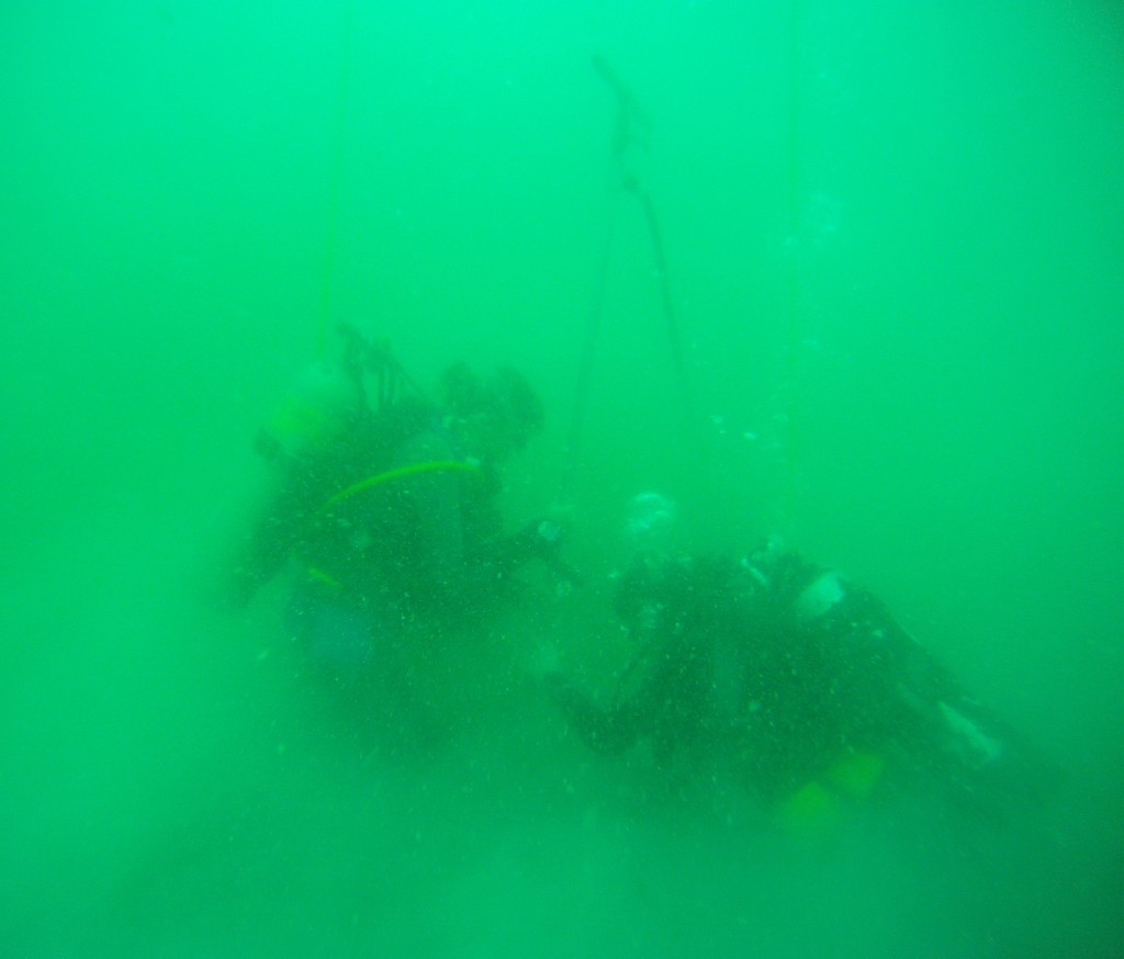 Divers using a hydraulic probe to ground truth a potential site.
